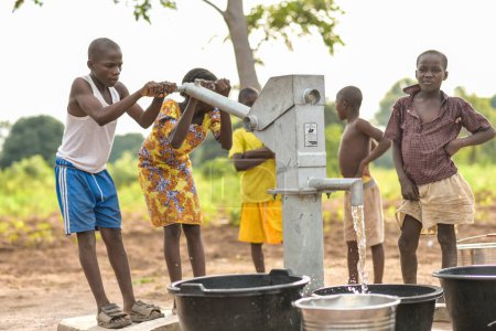 Téléchargez les photos : Talata, État du Plateau - 2 avril 2023 : Des enfants autochtones africains vont chercher de l'eau dans une pompe à main indienne nouvellement construite. Les membres de la communauté vont chercher de l'eau pour usage domestique. - en image libre de droit