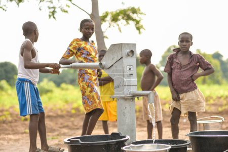 Foto de Talata, Plateau State - 2 de abril de 2023: Niños indígenas africanos que buscan agua de una bomba de mano india recién construida. Miembros de la comunidad que buscan agua para uso doméstico. - Imagen libre de derechos