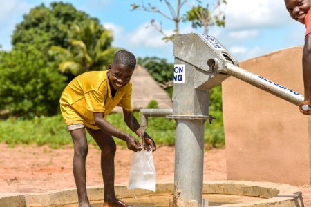 Téléchargez les photos : Talata, État du Plateau - Juin, 2023 : Des garçons africains récupèrent de l'eau d'une pompe à main indienne nouvellement construite. Les membres de la communauté vont chercher de l'eau pour usage domestique. - en image libre de droit