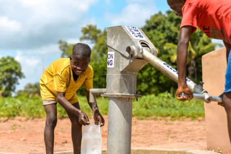 Téléchargez les photos : Talata, État du Plateau - Juin, 2023 : Des garçons africains récupèrent de l'eau d'une pompe à main indienne nouvellement construite. Les membres de la communauté vont chercher de l'eau pour usage domestique. - en image libre de droit