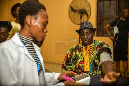 Téléchargez les photos : Abuja, Nigéria - vers août 2023 : Homme africain avec médecin dans une communauté rurale. Campagne politique en Afrique - en image libre de droit