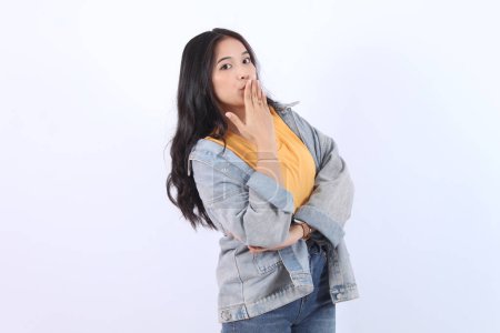 Shocked young Asian woman wearing blue jacket yellow t-shirt covering mouth and close mouth with hands expression face disgusting,  Isolated on white background.