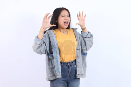 Jeune belle femme asiatique portant veste bleue jaune t-shirt bouche ouverte rugi faisant geste griffe comme chat, expression agressive et sexy