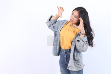 Photo for Young beautiful Asian woman wearing blue jacket yellow t-shirt open mouth roared doing claw gesture as cat, aggressive and sexy expression - Royalty Free Image