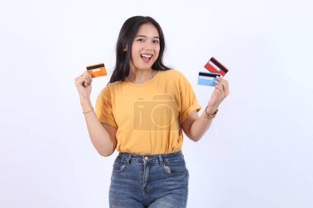 Aufgeregte Asiatin mit Kreditkarten. Glückliches Model-Mädchen trägt lässige T-Shirt-Kleidung zeigt Mitgliedskarte präsentiert Kreditkarte Kreditbank für Online-Shopping Zahlung Geld finanzielle Online