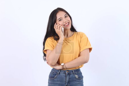 Friendly smiling asian woman talking on phone, girl on call, holding smartphone and laughing, speaking, standing over white background