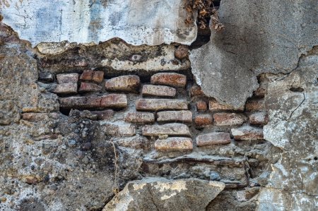 Téléchargez les photos : Un vieux mur de briques qui est poreux et qui s'érode jusqu'à ce que les briques soient visibles parce que le ciment se détache - en image libre de droit