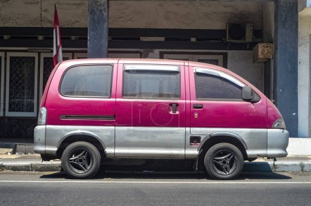Téléchargez les photos : Une vieille voiture rouge garée sur le côté d'une autoroute urbaine, Indonésie, 17 septembre 2023. - en image libre de droit