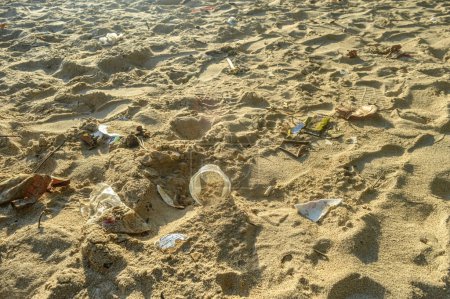 The beach sand is dirty because of plastic mineral water cups