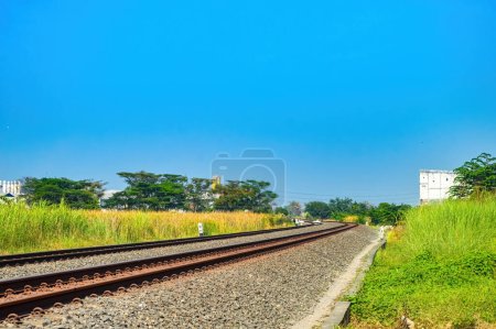Téléchargez les photos : Double voie ferrée qui courbe à travers le nord de l'île de Java avec un ciel bleu vif - en image libre de droit