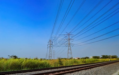 two towers of high-voltage electricity poles that cross over the double-track railroad tracks