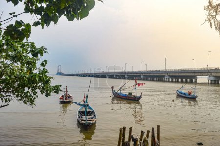 Photo for Landscape view of the Suramadu Bridge which stretches over the Madura Strait with several fishing boats - Royalty Free Image
