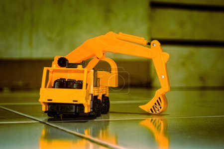 a yellow toy miniature excavator on the floor
