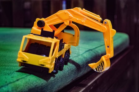 a yellow miniature excavator toy on the sofa
