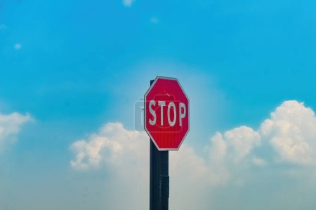 Foto de Una señal de parada de tráfico con un cielo azul nublado en el fondo - Imagen libre de derechos