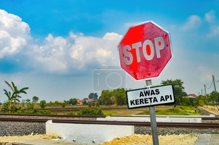 ein Stoppschild mit einem zweigleisigen Bahngleis im Hintergrund