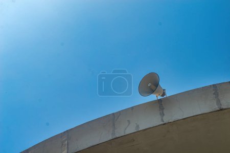 vintage horn speaker mounted on the roof with bright blue sky background