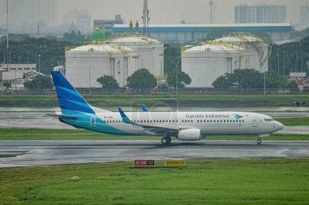 Foto de Un avión Boeing B737-8U3 perteneciente a la aerolínea Garuda Indonesia despega en la pista del Aeropuerto Internacional de Juanda Surabaya en Sidoarjo durante la lluvia, Indonesia, 6 de enero de 2024 - Imagen libre de derechos