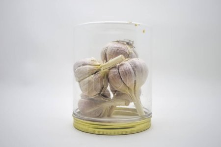 a bunch of garlic in a plastic jar turned upside down isolated on white background