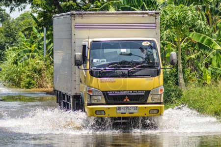 Téléchargez les photos : Un camion-citerne logistique traversant les eaux d'inondation dans le district de Gresik, Indonésie, 21 février 2024. - en image libre de droit