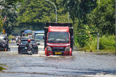 Photo for Several vehicles such as trucks, bicycles and cars were trapped by floodwater in Gresik Regency, Indonesia, 21 February 2024. - Royalty Free Image