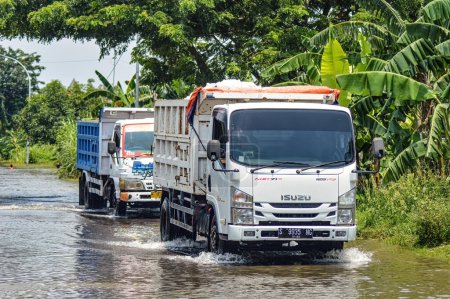 Photo for Dump truck crashing through floodwater in Gresik Regency, Indonesia, 21 February 2024. - Royalty Free Image