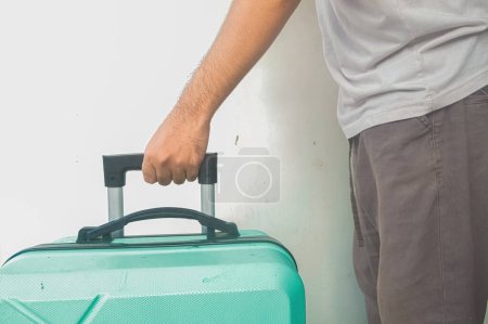 la mano de un hombre sosteniendo una maleta verde turquesa