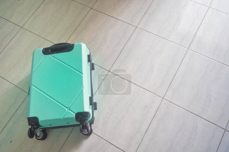 Téléchargez les photos : Une valise verte turquoise posée sur le sol - en image libre de droit