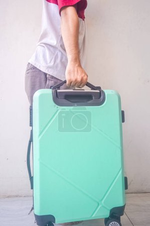 hombre maduro tirando de una maleta verde turquesa