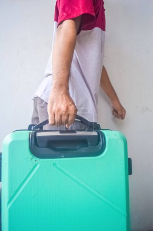 Älterer Mann zieht einen türkisgrünen Koffer