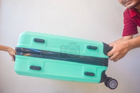 Téléchargez les photos : Un homme adulte et un petit enfant ont soulevé une valise verte turquoise - en image libre de droit