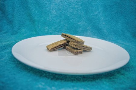 Photo for Several wafers or wafers arranged on a plain white plate on a turquoise background - Royalty Free Image