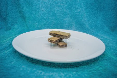 several wafers or wafers arranged on a plain white plate on a turquoise background