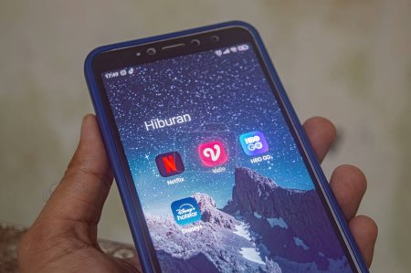 Foto de Mano sosteniendo un teléfono inteligente Xiaomi Android con una pantalla que muestra una colección de reproductor de películas o aplicaciones de cine en línea, Indonesia, 12 de mayo de 2024. - Imagen libre de derechos