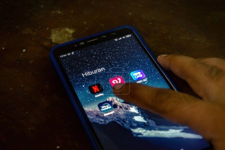 Foto de Mano tocando un teléfono inteligente Xiaomi Android con una pantalla que muestra una colección de reproductor de películas o aplicaciones de cine en línea, Indonesia, 12 de mayo de 2024. - Imagen libre de derechos