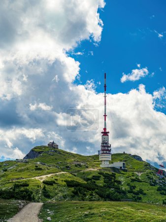 TV radio tower and chapel on the top of the mountain Dobratsch in Carinthia, Austria, summer, cloudy dramatic sky, wildflowers alpine landscape