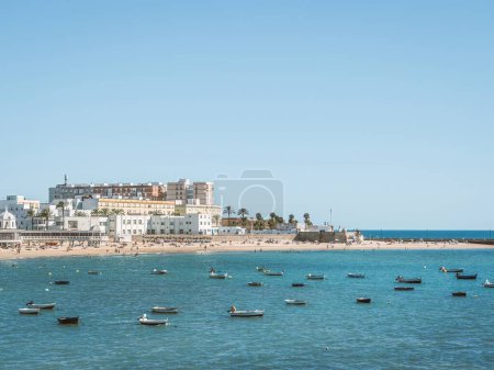 Foto de Barcos anclados y personas tomando el sol en una playa de arena de verano Playa de La Caleta en Cádiz, Andalucía, España - Imagen libre de derechos