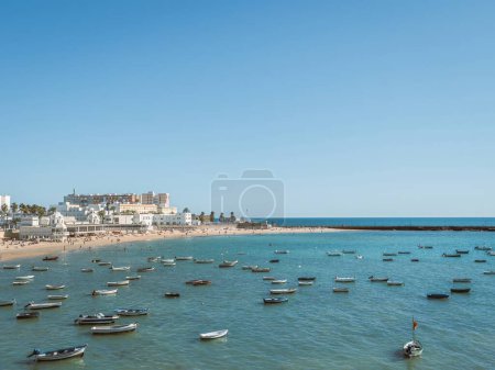 Foto de Barcos anclados y personas tomando el sol en una playa de arena de verano Playa de La Caleta en Cádiz, Andalucía, España - Imagen libre de derechos