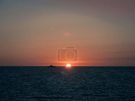 Ein Militärschiff der spanischen Marine am Horizont bei Sonnenuntergang in Cadiz, Andalusien, Spanien