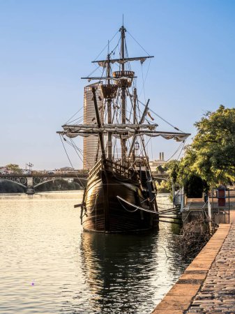 Le navire carrack réplique Nao Victoria amarré à la rivière Guadalquivir dans le centre historique de Séville, Espagne, coucher de soleil heure dorée