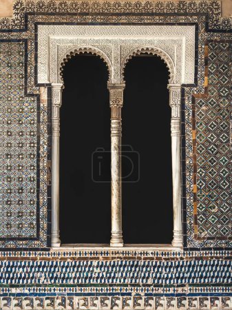 A classic Arabic Andalusian window framed with ornamental carvings and painted tiles in the Casa de Pilatos in Seville, Spain, empty window copy space