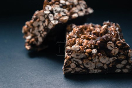 Chocolate puffed rice bars on a granite plate, dark background, closeup