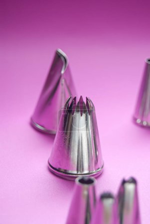 Baking tools, variety of piping tips on a pink background