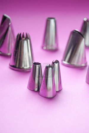Foto de Herramientas para hornear, variedad de puntas de tuberías sobre un fondo rosa - Imagen libre de derechos