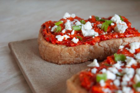 Photo for Ajvar traditional Balkan homemade red pepper paste on a slice of bread with white cheese and spring onions - Royalty Free Image