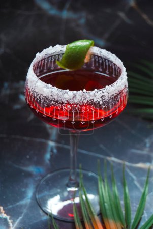 Roter alkoholischer Cocktail, Limettengarnitur, gesalzener Rand, Marmorhintergrund, kunstvolles Glas, Elfenlichter