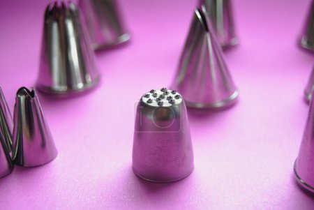 Baker piping tips on a pink background, nozzles, cake decorating, metallic, stainless steel baking tools, closeup