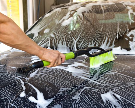 The car undergoes a thorough cleaning with high pressure water in an open car wash.