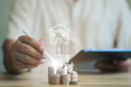 Businessman pointing at stack of coins in mock house with arrow pointing upwards Concept of saving money to buy a house Arrange the coins in a growing graph.