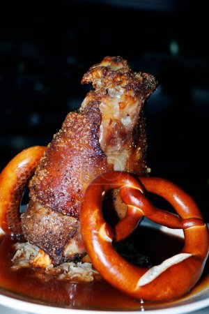 Photo for Roasted crispy pork knuckle with german pretzel and gravy in close up - Royalty Free Image